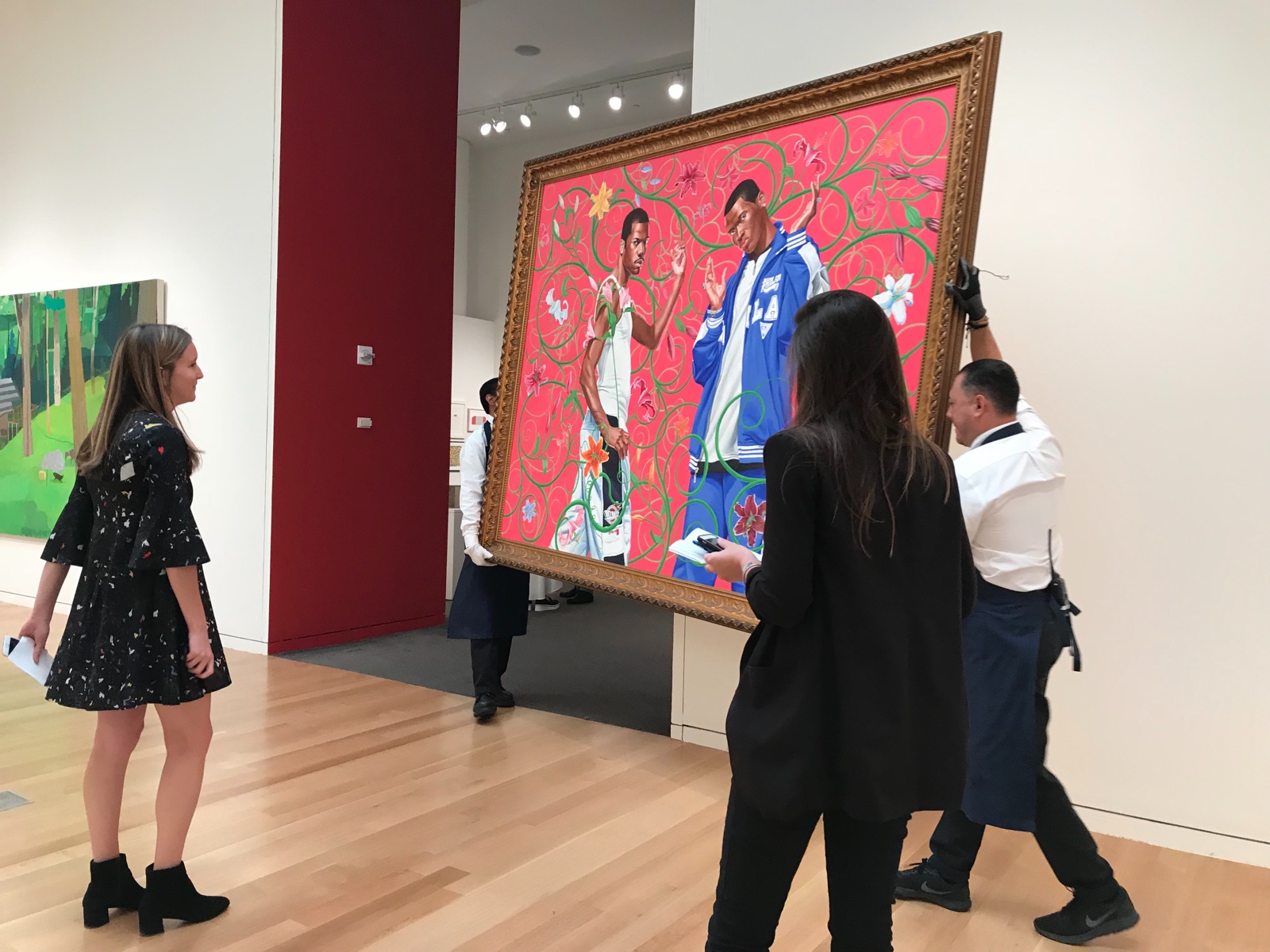 Art handlers transporting a large framed painting through a gallery